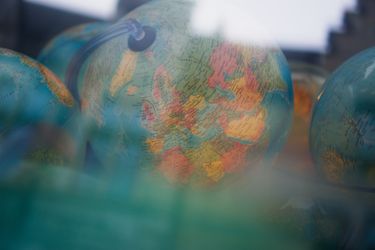 Close-up of several globes, focusing on Europe. The foreground is blurred, and the background shows dim lighting.